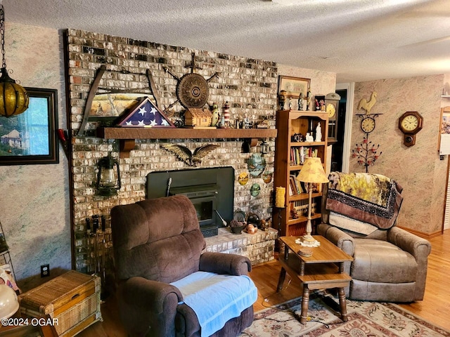 living room with hardwood / wood-style flooring, a textured ceiling, and a brick fireplace