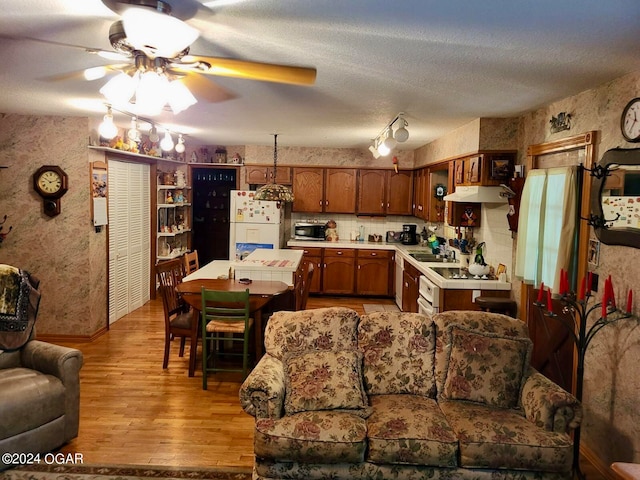 living room featuring a textured ceiling, ceiling fan, sink, and light hardwood / wood-style floors