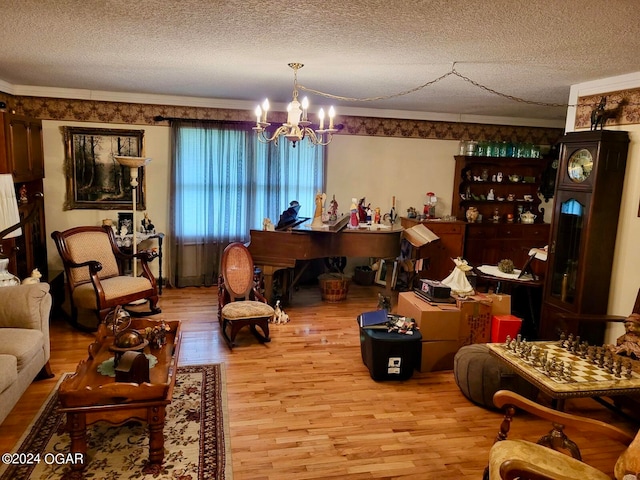 interior space with ornamental molding, a textured ceiling, a notable chandelier, and light hardwood / wood-style floors