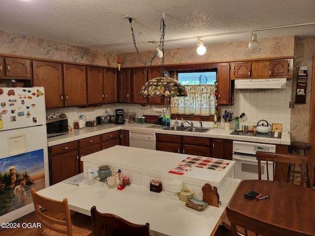 kitchen with decorative light fixtures, white appliances, sink, tasteful backsplash, and a textured ceiling