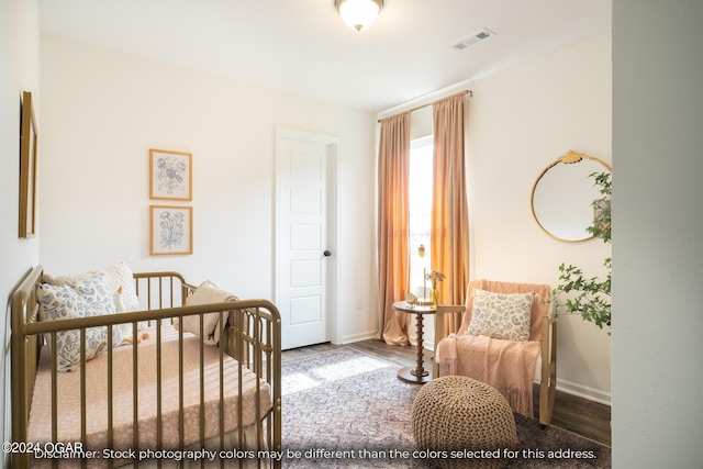 bedroom with wood-type flooring and a nursery area