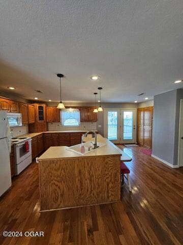 kitchen featuring white appliances, dark hardwood / wood-style flooring, and a kitchen island with sink