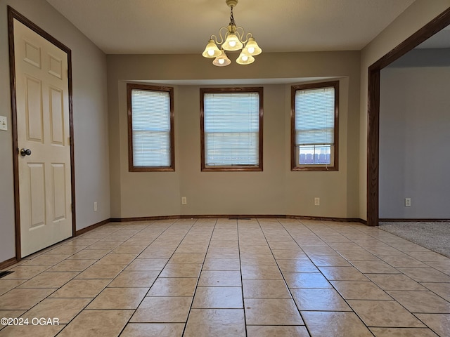 spare room featuring a notable chandelier and light tile patterned floors