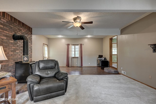 9825 County Rd 215, Webb City, MO 64870 - carpeted living room with a wood stove, ceiling fan, baseboards, and a textured ceiling