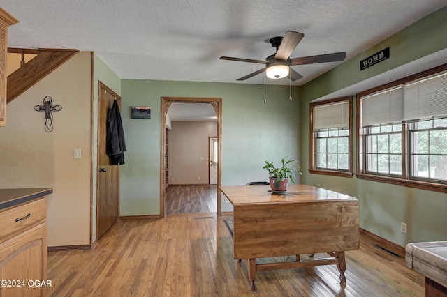 9825 County Rd 215, Webb City, MO 64870 - dining room with light wood-style flooring, baseboards, ceiling fan, and a textured ceiling