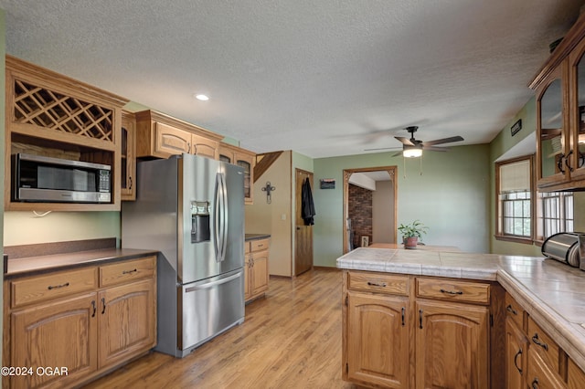 9825 County Rd 215, Webb City, MO 64870 - kitchen featuring stainless steel appliances, a textured ceiling, ceiling fan, light wood-type flooring, and glass insert cabinets