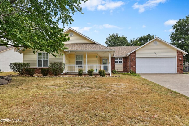 view of front of property with a front yard, a garage, and a porch