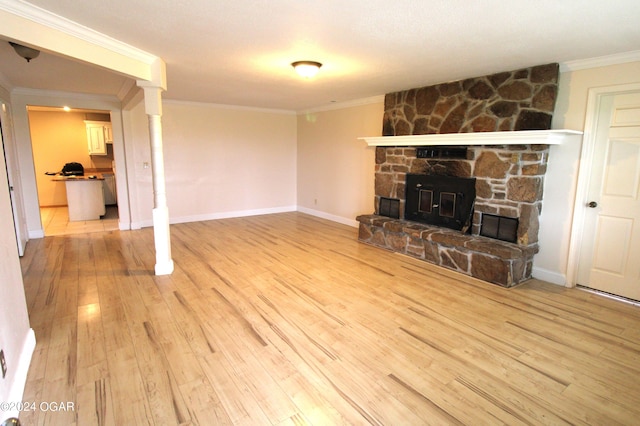 unfurnished living room featuring light hardwood / wood-style floors, crown molding, and a stone fireplace