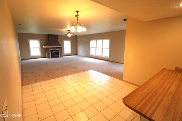 unfurnished living room with a healthy amount of sunlight, ceiling fan with notable chandelier, and light carpet