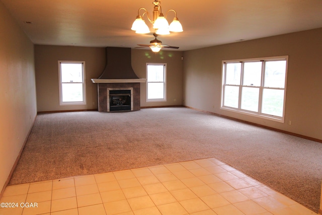 unfurnished living room with light carpet, ceiling fan with notable chandelier, and a fireplace