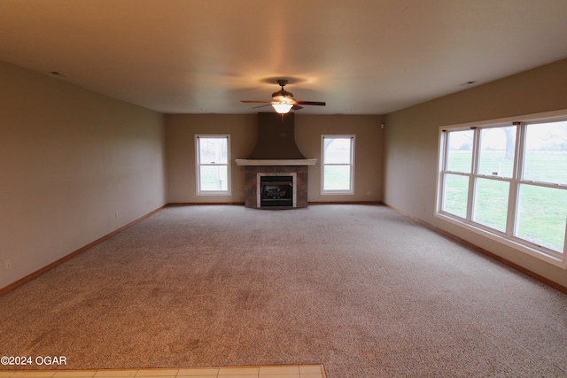 unfurnished living room featuring ceiling fan, light colored carpet, and a tiled fireplace