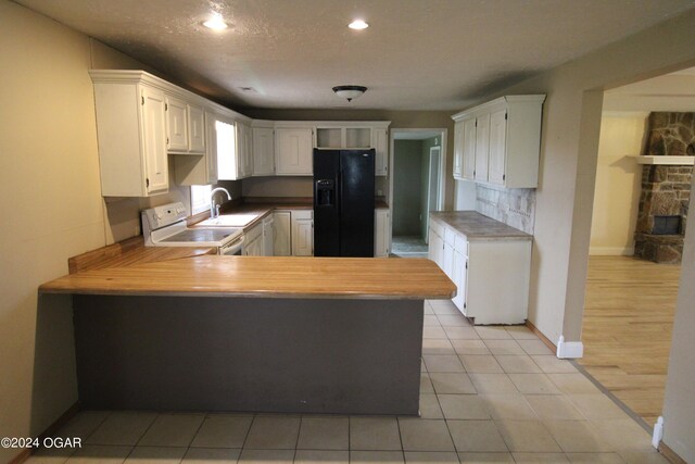 kitchen featuring kitchen peninsula, black refrigerator with ice dispenser, electric range, and white cabinetry