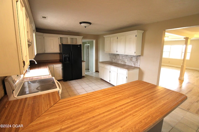 kitchen with black fridge, stove, white cabinetry, light wood-type flooring, and decorative backsplash