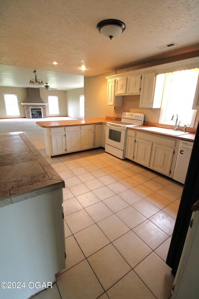 kitchen featuring white range with electric cooktop, light tile patterned floors, sink, and a wealth of natural light