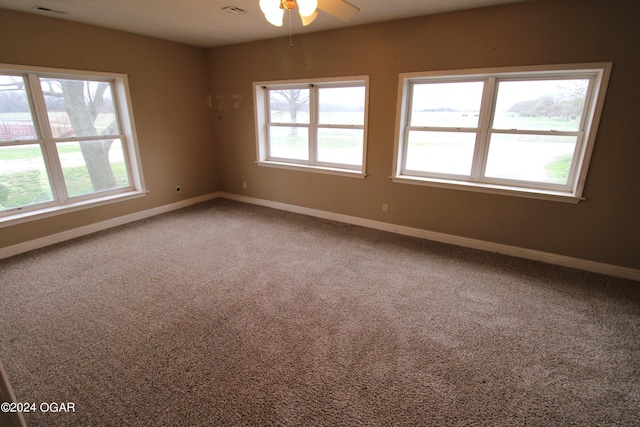 carpeted spare room featuring a healthy amount of sunlight and ceiling fan