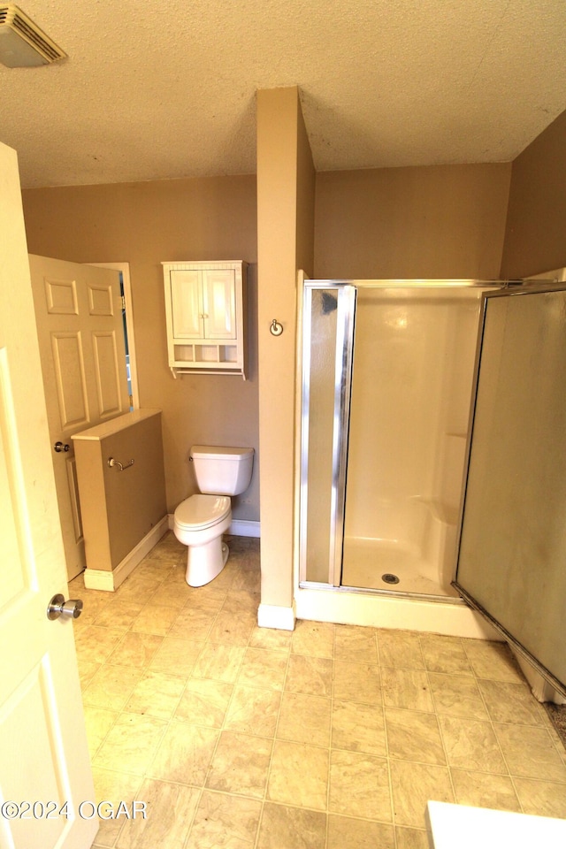 bathroom featuring a textured ceiling, toilet, and an enclosed shower