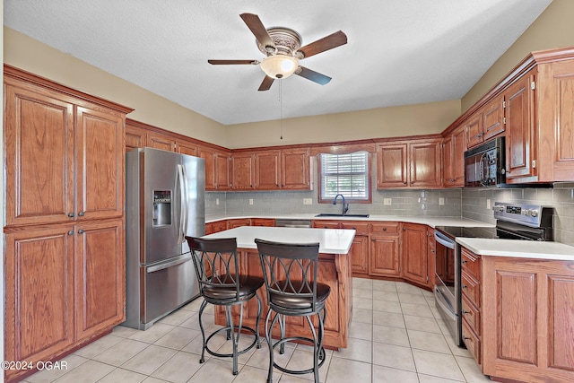 kitchen featuring a center island, a breakfast bar area, sink, stainless steel appliances, and ceiling fan