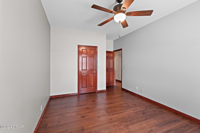 unfurnished bedroom featuring ceiling fan and dark hardwood / wood-style flooring