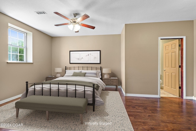 bedroom featuring a textured ceiling, connected bathroom, dark wood-type flooring, and ceiling fan