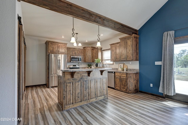 kitchen with stainless steel appliances, a center island, plenty of natural light, and a breakfast bar area