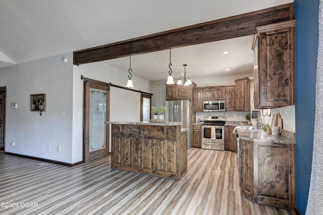 kitchen with appliances with stainless steel finishes, hanging light fixtures, a kitchen island, beamed ceiling, and light wood-type flooring