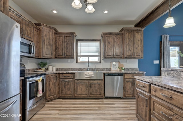 kitchen with stainless steel appliances, plenty of natural light, sink, and light hardwood / wood-style flooring