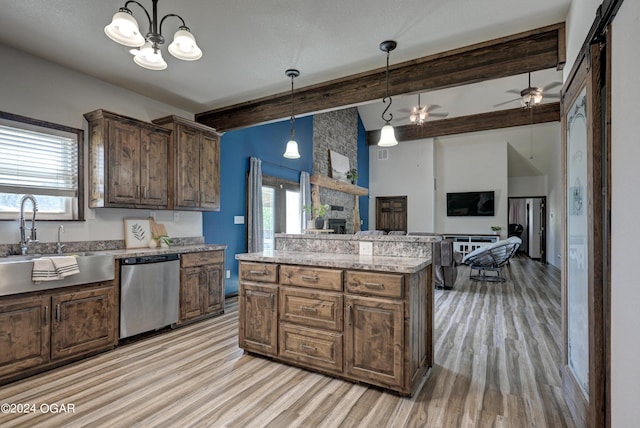 kitchen with a stone fireplace, ceiling fan with notable chandelier, stainless steel dishwasher, and a wealth of natural light