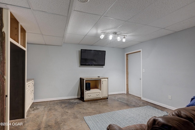 unfurnished living room with concrete flooring and a paneled ceiling