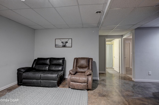 living room with concrete flooring and a drop ceiling