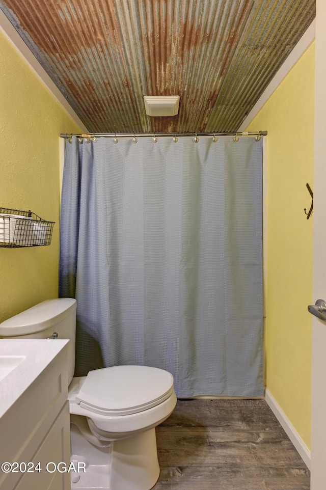 bathroom featuring vanity, hardwood / wood-style flooring, walk in shower, and toilet