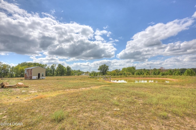 view of yard featuring a storage unit, a water view, and a rural view