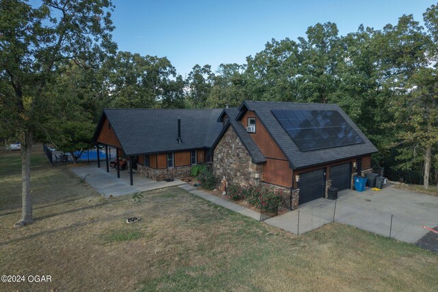 view of front facade featuring a garage, solar panels, and a front lawn