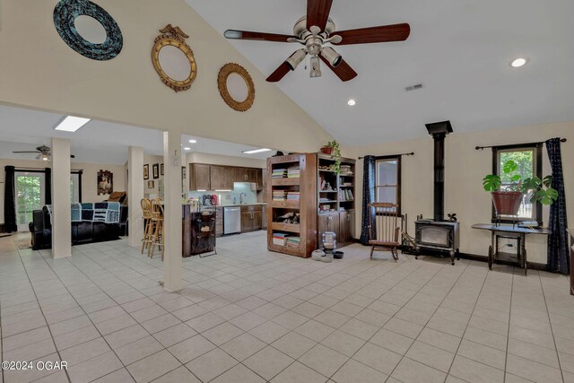 unfurnished living room featuring high vaulted ceiling, a wood stove, ceiling fan, and light tile patterned floors