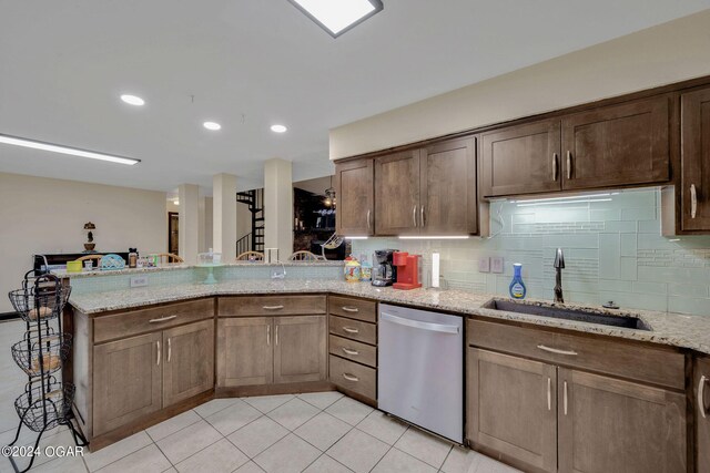 kitchen featuring light stone counters, light tile patterned floors, sink, kitchen peninsula, and stainless steel dishwasher