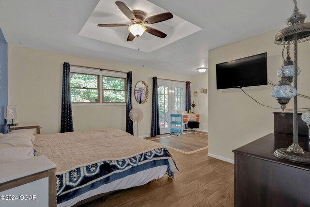 bedroom with ceiling fan, hardwood / wood-style flooring, and a raised ceiling