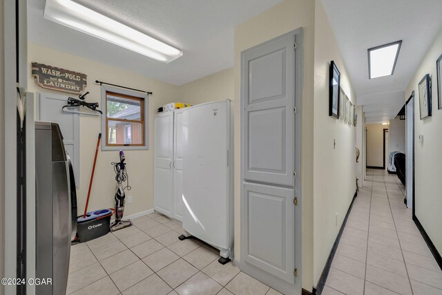 kitchen featuring white cabinets, light tile patterned flooring, and white fridge