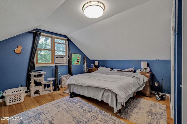 bedroom with wood-type flooring, vaulted ceiling, and cooling unit