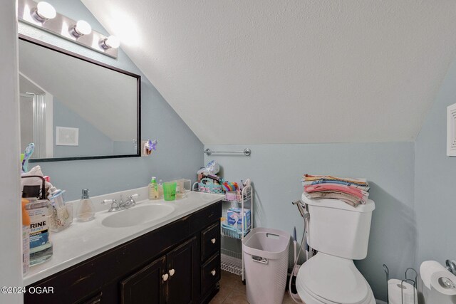 bathroom featuring tile patterned flooring, lofted ceiling, vanity, and toilet