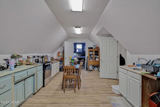 kitchen with sink, stainless steel range with electric stovetop, a textured ceiling, light wood-type flooring, and vaulted ceiling