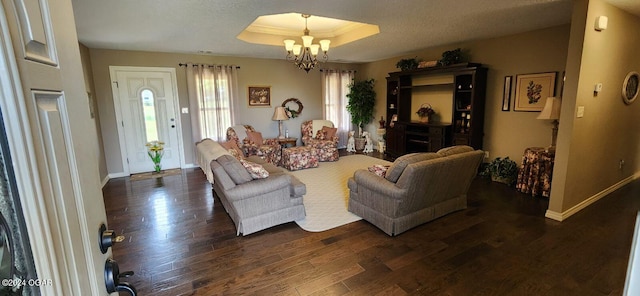 living room with an inviting chandelier, a tray ceiling, and dark hardwood / wood-style flooring