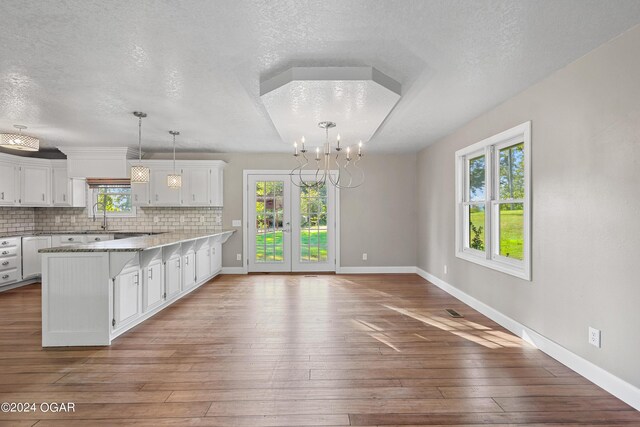 kitchen featuring a textured ceiling, a healthy amount of sunlight, wood-type flooring, and white cabinets