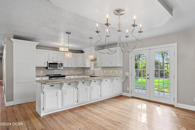 kitchen featuring appliances with stainless steel finishes, light hardwood / wood-style floors, decorative light fixtures, and white cabinets