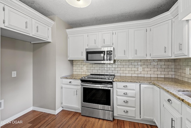 kitchen with appliances with stainless steel finishes, dark wood-type flooring, and white cabinets