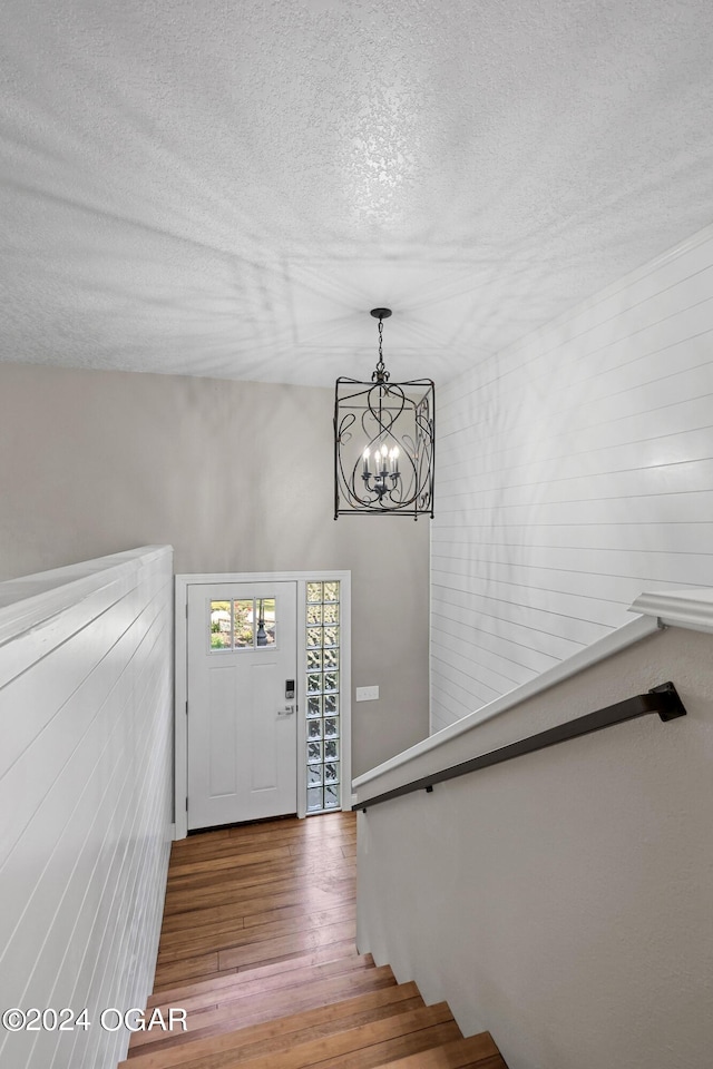 foyer entrance featuring an inviting chandelier, a textured ceiling, and hardwood / wood-style floors