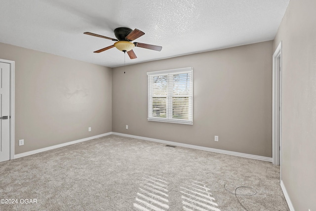 spare room featuring a textured ceiling, ceiling fan, and light colored carpet