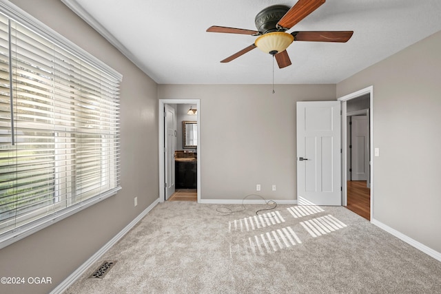 unfurnished bedroom with connected bathroom, ceiling fan, and light colored carpet