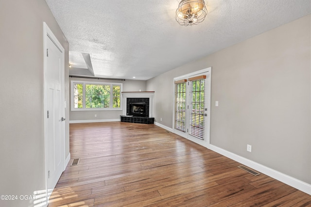 unfurnished living room with a textured ceiling, a fireplace, and hardwood / wood-style floors