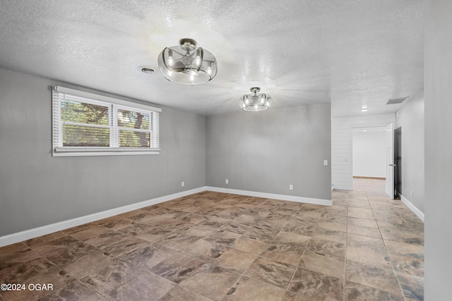 unfurnished room with a textured ceiling