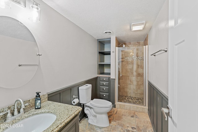 bathroom with a textured ceiling, walk in shower, vanity, and toilet