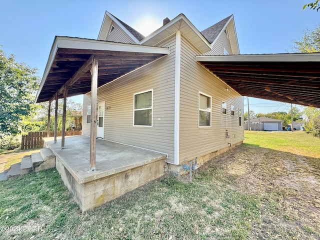 view of side of home featuring a storage unit, a patio, and a lawn